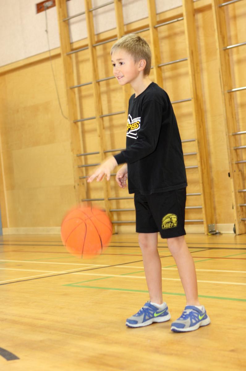 young boy dribbling a basketball in place